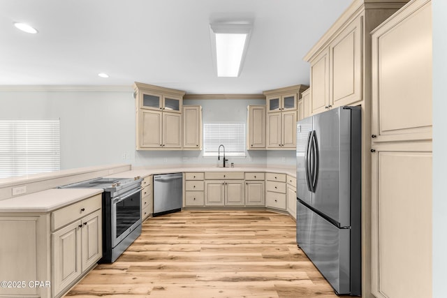 kitchen with sink, stainless steel appliances, ornamental molding, cream cabinetry, and light wood-type flooring