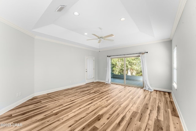 empty room featuring ceiling fan, light wood-type flooring, crown molding, and a tray ceiling