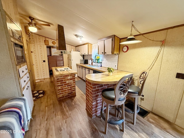 kitchen with vaulted ceiling, exhaust hood, wood-type flooring, white refrigerator, and butcher block countertops