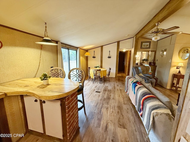 dining room with lofted ceiling with beams, hardwood / wood-style flooring, and ceiling fan