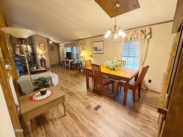 dining room with light wood-type flooring, crown molding, and a notable chandelier