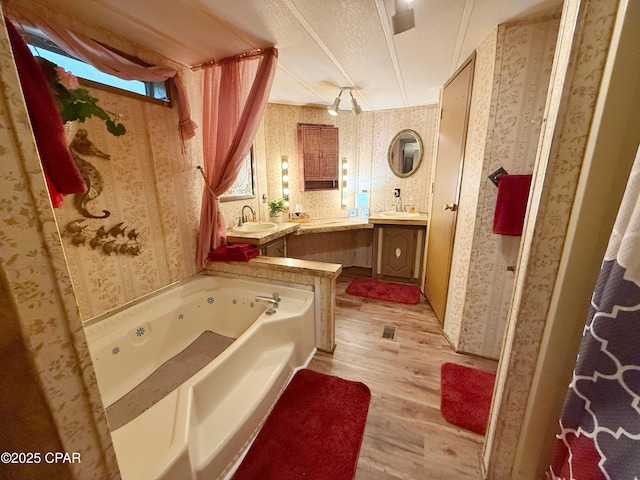 bathroom with a tub, vanity, a textured ceiling, and hardwood / wood-style flooring