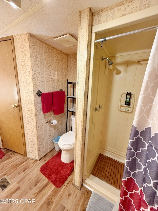 bathroom featuring a shower, hardwood / wood-style floors, and toilet