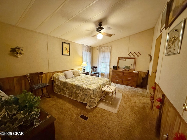 carpeted bedroom featuring wooden walls, ceiling fan, and lofted ceiling