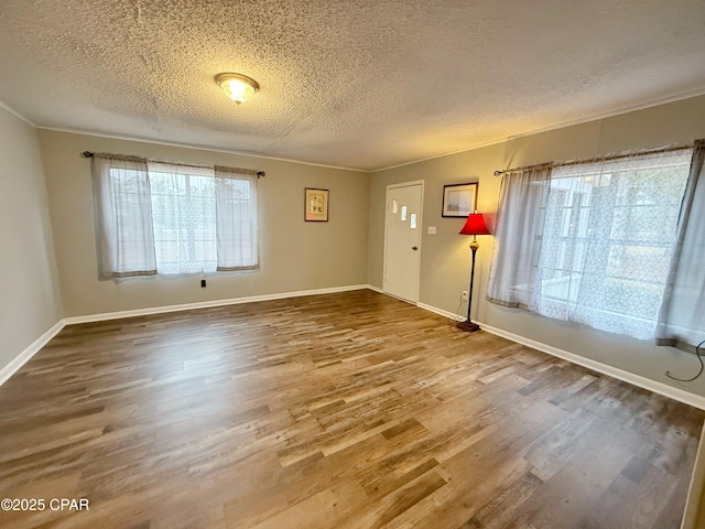 unfurnished room with hardwood / wood-style floors, crown molding, and a textured ceiling