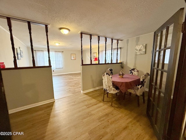 dining area with a textured ceiling, wood-type flooring, and crown molding