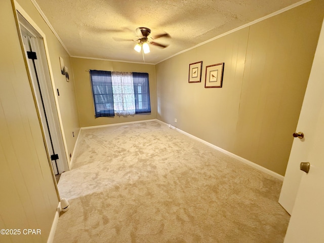 spare room featuring ceiling fan, ornamental molding, a textured ceiling, and light carpet