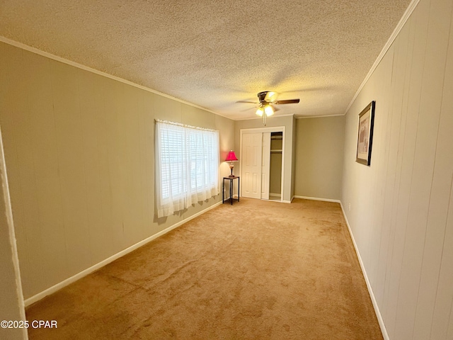 interior space featuring ceiling fan, light colored carpet, wood walls, and ornamental molding