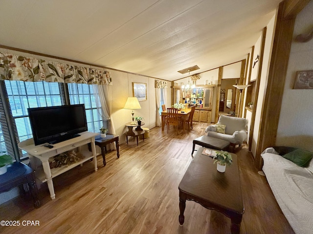 living room with hardwood / wood-style floors, vaulted ceiling, and a notable chandelier