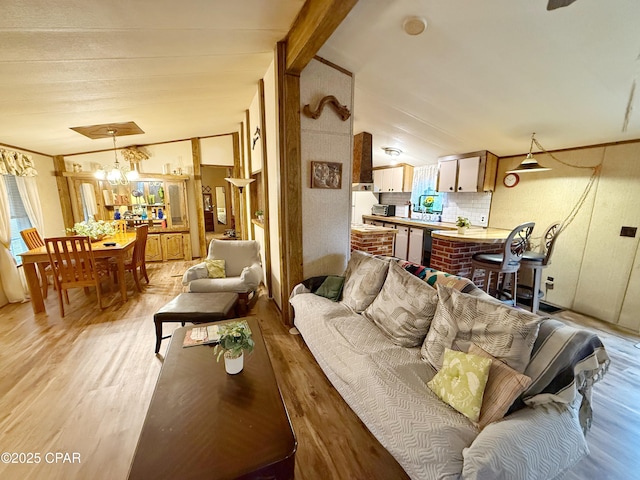 living room with light wood-type flooring, vaulted ceiling, and an inviting chandelier