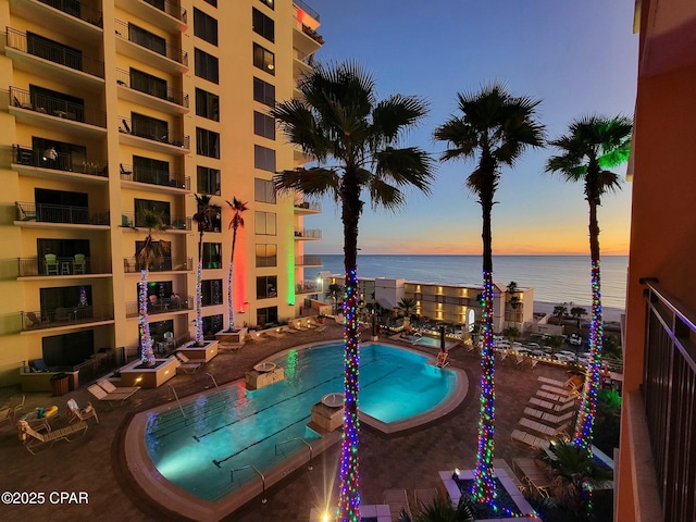 pool at dusk with a water view and a patio