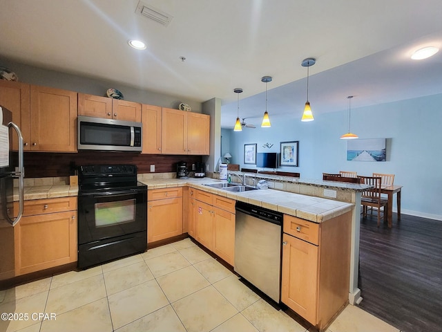 kitchen with sink, stainless steel appliances, kitchen peninsula, decorative light fixtures, and light tile patterned floors