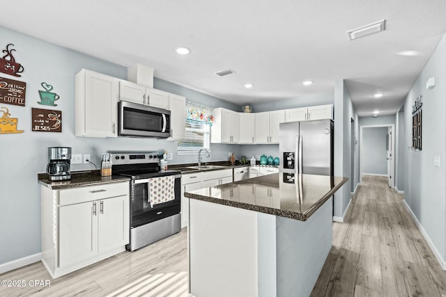 3111 E 2nd Plz, Panama City, FL 32401 - kitchen featuring appliances with stainless steel finishes, a sink, light wood-style flooring, white cabinetry, and a kitchen island
