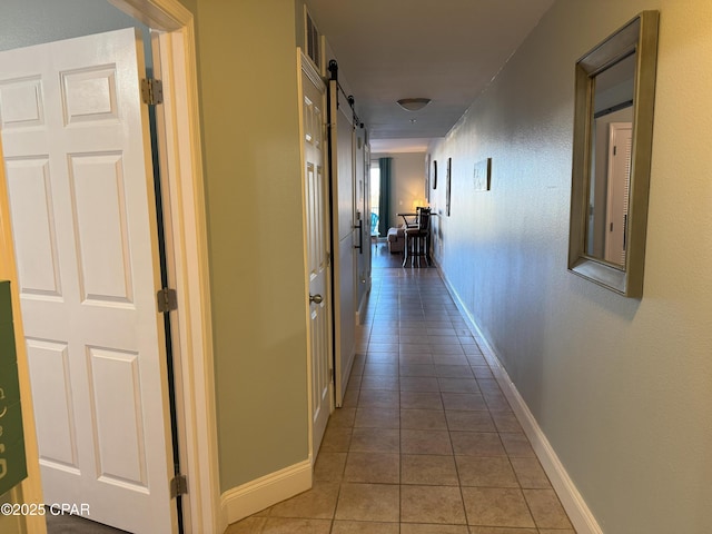 hallway featuring a barn door and light tile patterned floors