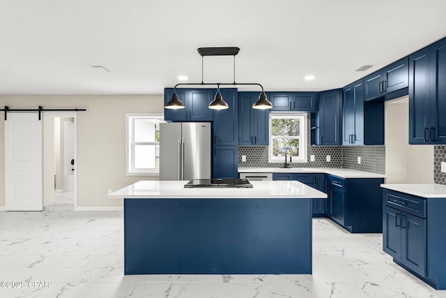 kitchen with blue cabinetry, a barn door, stainless steel fridge, and a kitchen island