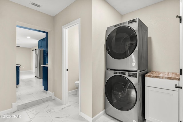 washroom featuring cabinets and stacked washer and dryer