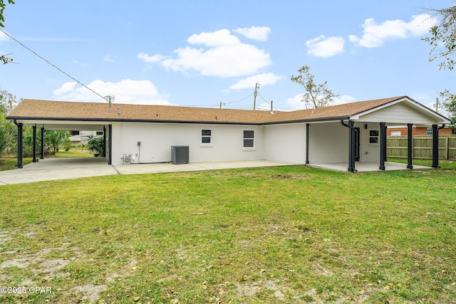 rear view of house featuring a lawn, central AC unit, and a carport