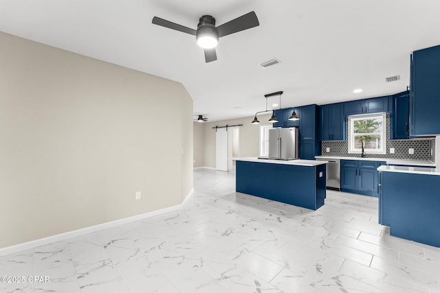 kitchen featuring appliances with stainless steel finishes, backsplash, ceiling fan, a center island, and hanging light fixtures