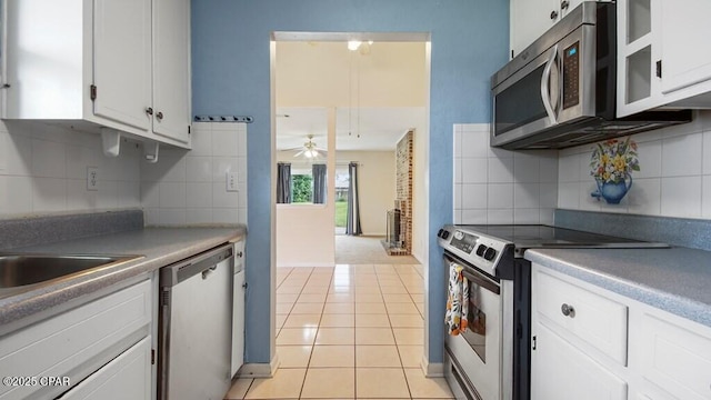 kitchen featuring white cabinetry, stainless steel appliances, light tile patterned flooring, and backsplash