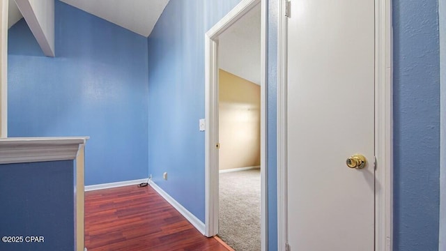 hallway with dark wood-type flooring and lofted ceiling