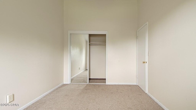 unfurnished bedroom featuring light carpet and a closet