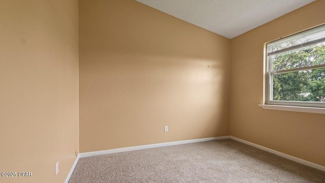 carpeted spare room with vaulted ceiling