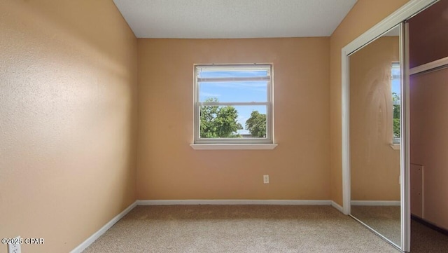 unfurnished bedroom featuring light carpet and a closet