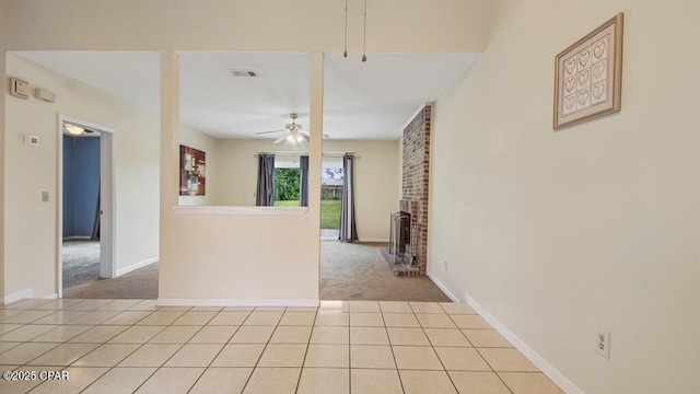 unfurnished room featuring light carpet, a fireplace, and ceiling fan