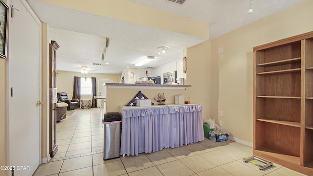 interior space featuring rail lighting, light tile patterned floors, a textured ceiling, and kitchen peninsula