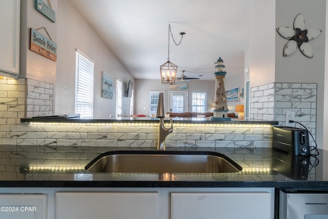 kitchen featuring sink, ceiling fan, white cabinetry, tasteful backsplash, and decorative light fixtures