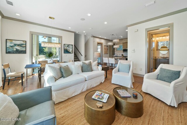 living room featuring ornamental molding, a wealth of natural light, and light hardwood / wood-style flooring