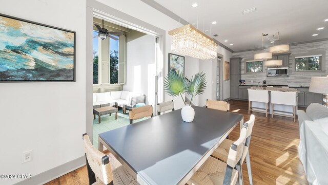 dining area with ceiling fan with notable chandelier and light hardwood / wood-style flooring