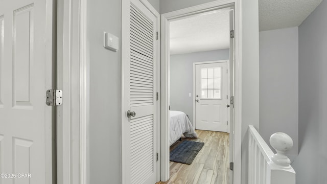 corridor with light hardwood / wood-style floors and a textured ceiling