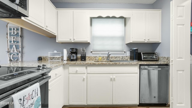 kitchen featuring sink, light stone counters, white cabinetry, and stainless steel appliances