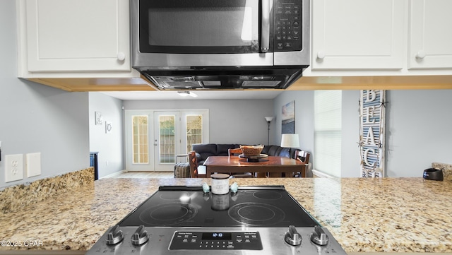 kitchen featuring light stone countertops, white cabinetry, and range