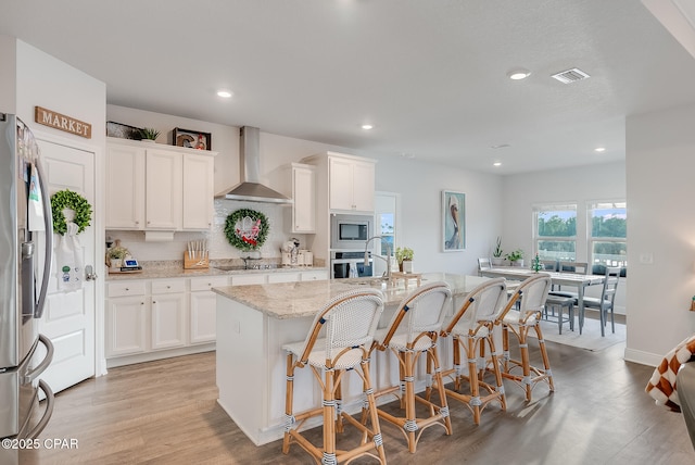 kitchen with wall chimney exhaust hood, stainless steel appliances, and white cabinets