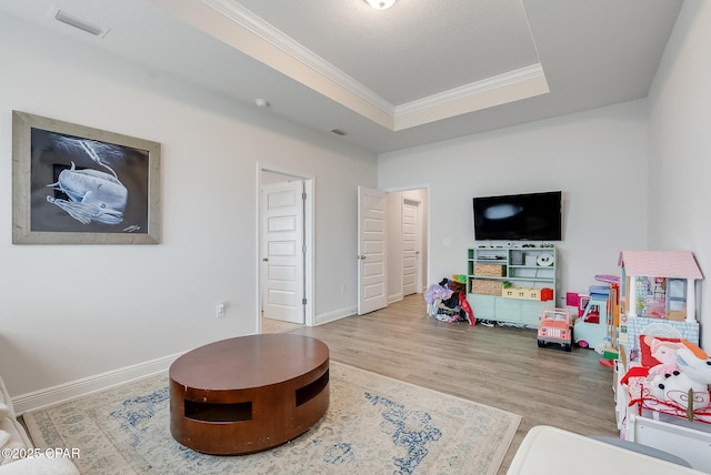 rec room with a raised ceiling, ornamental molding, and wood-type flooring