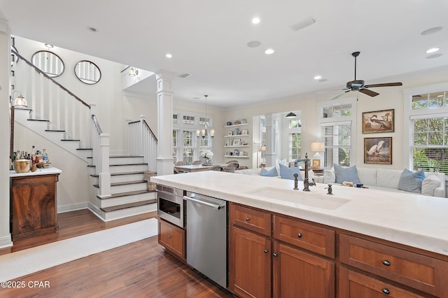 kitchen with stainless steel dishwasher, ceiling fan with notable chandelier, built in microwave, sink, and pendant lighting