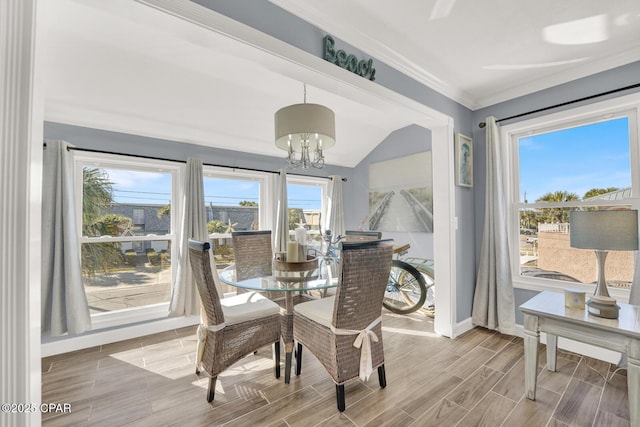 dining room featuring crown molding, a notable chandelier, wood finished floors, baseboards, and lofted ceiling