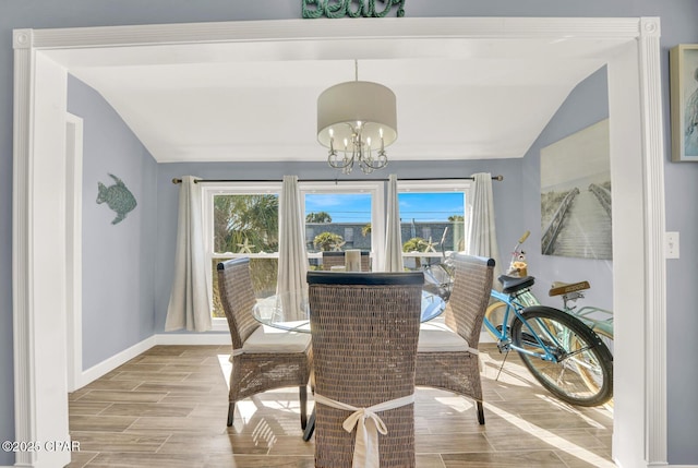 dining room with a notable chandelier, vaulted ceiling, wood finish floors, and baseboards
