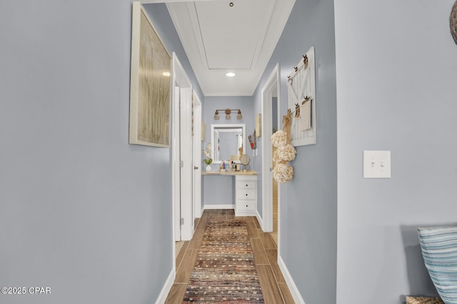 corridor featuring crown molding, attic access, baseboards, and wood tiled floor