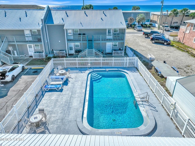 pool with a fenced backyard, a patio, a water view, and stairway
