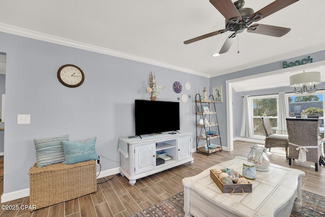 living room featuring baseboards, ornamental molding, ceiling fan with notable chandelier, and light wood-type flooring