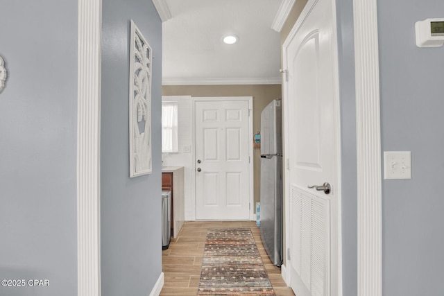 hall featuring crown molding, baseboards, light wood-style floors, and recessed lighting
