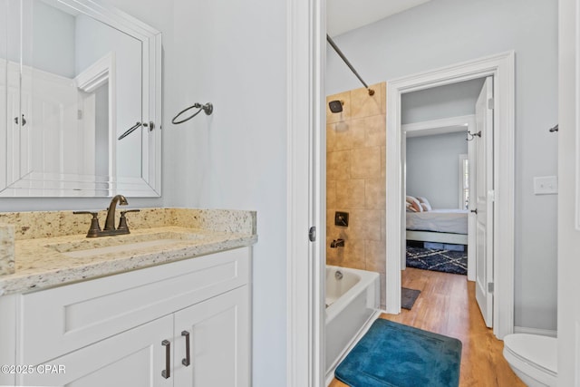 full bathroom featuring hardwood / wood-style floors, vanity, toilet, and tiled shower / bath