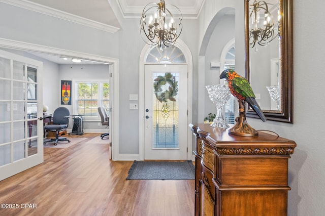 foyer with french doors, hardwood / wood-style flooring, an inviting chandelier, and crown molding