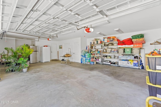 garage featuring a garage door opener, white fridge, and stainless steel refrigerator