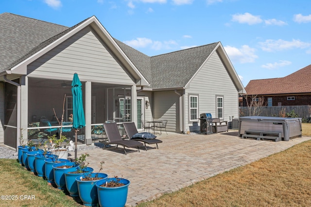 rear view of house with a patio area, a sunroom, and a hot tub