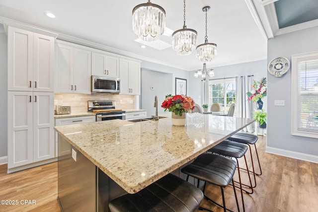 kitchen with a center island with sink, white cabinetry, and stainless steel appliances