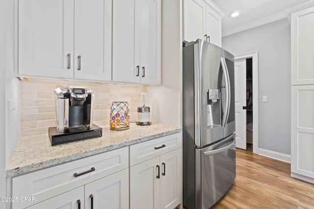 kitchen with white cabinets, stainless steel refrigerator with ice dispenser, backsplash, and light stone counters